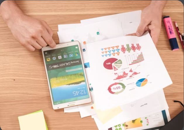 Printed reports and a tablet on a desk